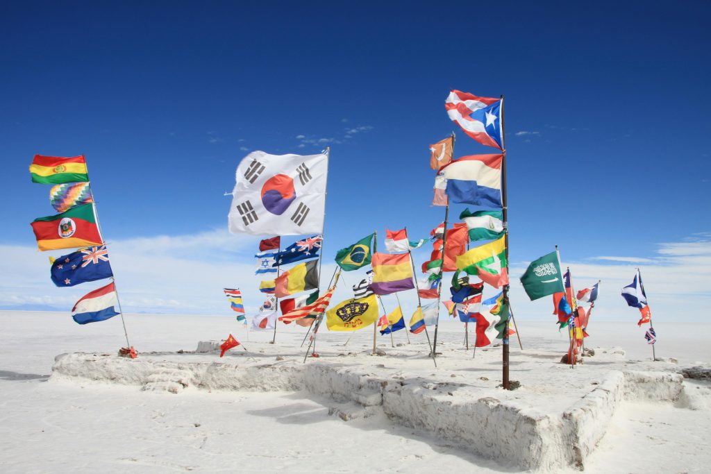 National flags waving on the Uyuni Salt Flats in Bolivia, showcasing global diversity.