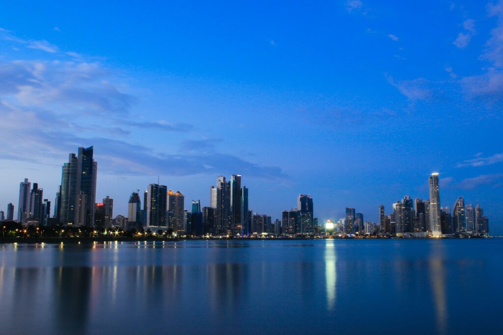 Stunning Panama City skyline with high-rise buildings and calm sea under a vibrant blue evening sky.